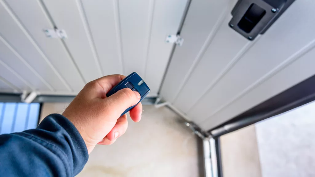 Man using a remote to open a Sectional Garage Door, showcasing one of the Types of Garage Doors discussed in our comprehensive comparison article.